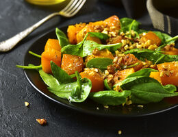 A spinach and sweet potato salad topped with nuts