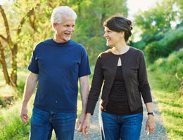 A middle-aged couple walks down a trail.